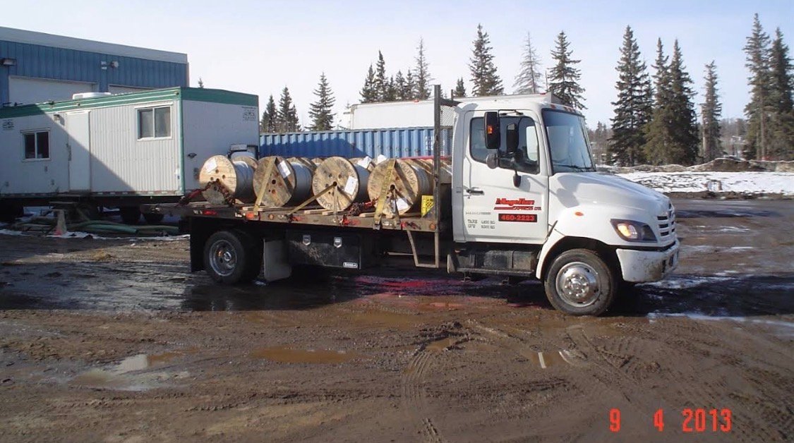 Flatbed truck loaded with industrial cable reels in a yard