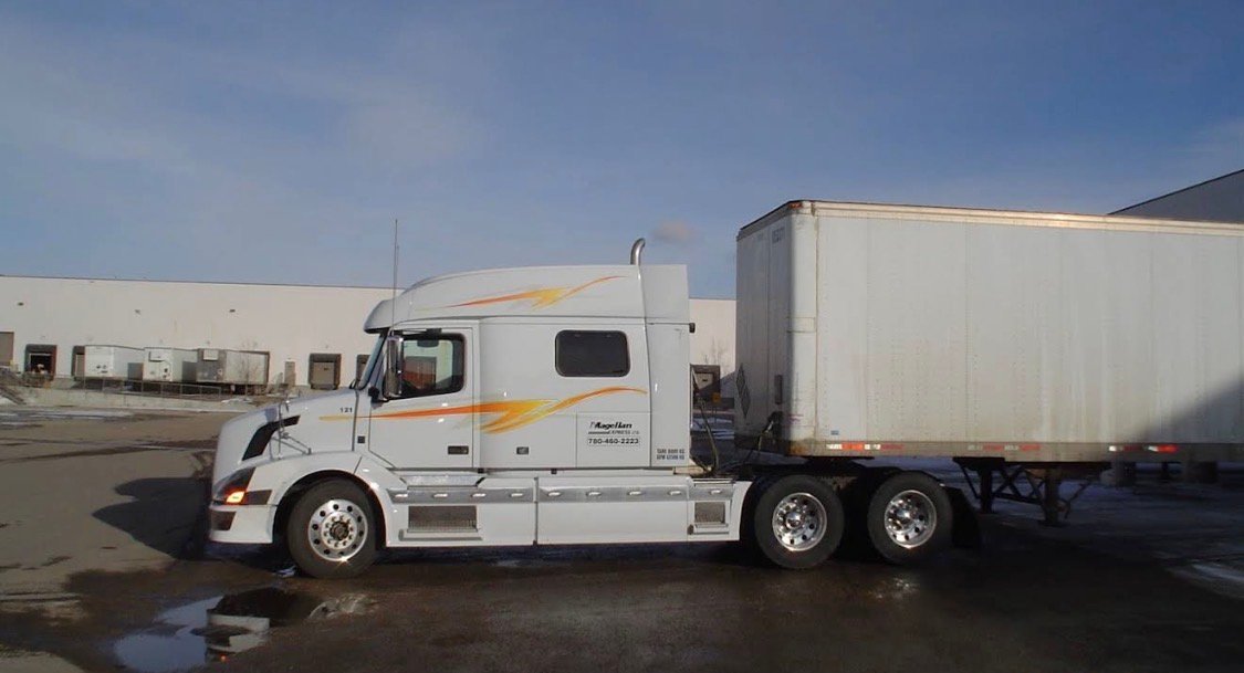 Sleeper tractor coupled to a dry van trailer at a loading dock